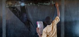 A student in a second grade class at the blackboard writing with chalk